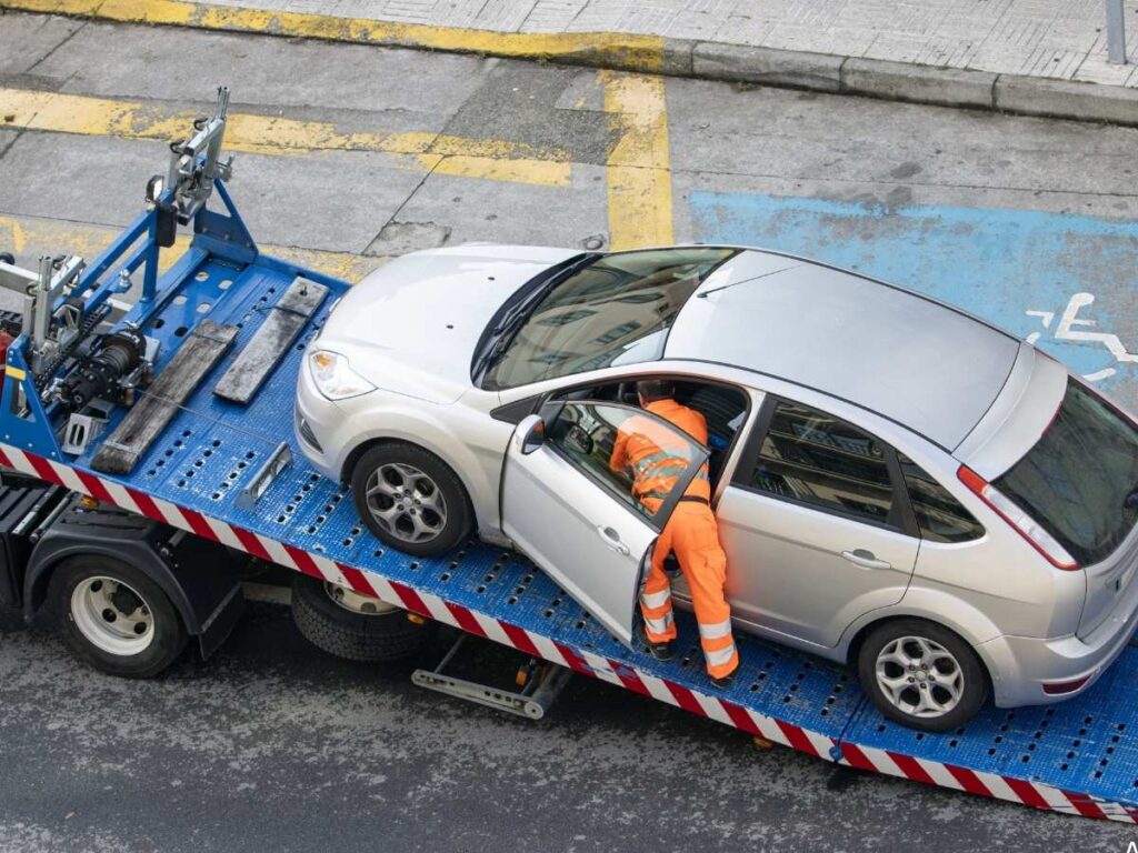 Worker repairing a broken-down vehicle after being transported by a fredericton towing company on a roadside service call